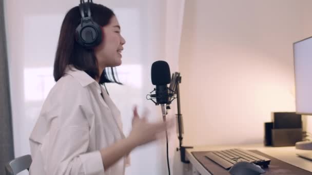 Nuori aasialainen naaras podcaster puhuu mikrofoniin tallentaessaan podcastia ja suoratoistosisältöä sosiaaliselle medialle. - Materiaali, video