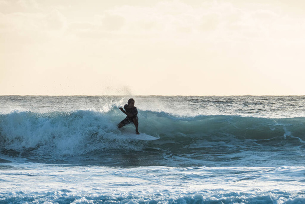 Молодой серфер катается на волне на закате - Фото, изображение