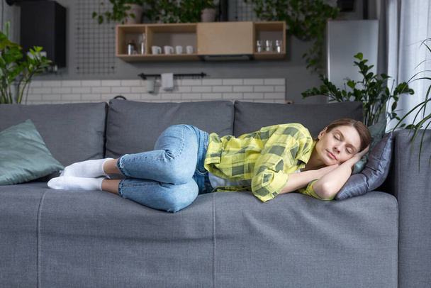 A middle-aged woman at home alone sleeps on a sofa resting from homework - 写真・画像