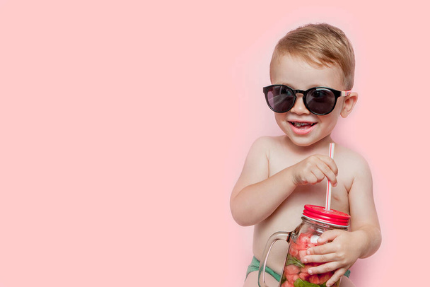 Boy in sunglasses enjoys drinking a cocktail with watermelon and mint. Posing on a pink background. - Zdjęcie, obraz
