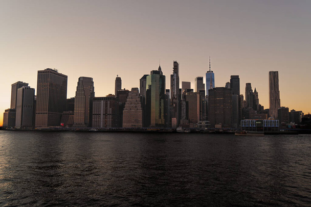 Scenic uitzicht op prachtige Manhattan skyline tijdens zonsondergang in New York City geschoten vanaf de overkant van de Hudson rivier van Brooklyn Bridge Park in New York City - Foto, afbeelding