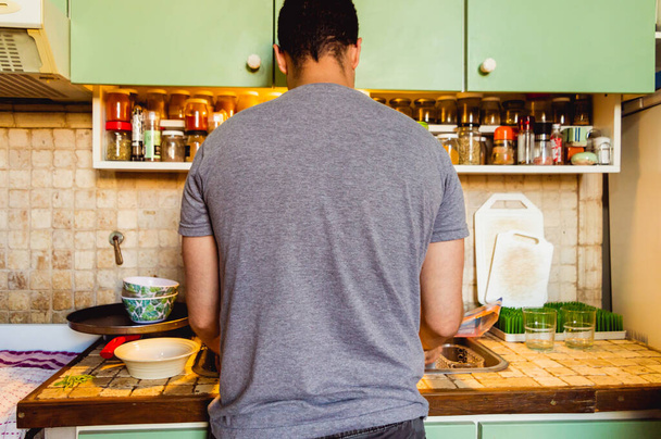 Fehér férfi házimunkát végez otthon, mosogatás a konyhájában.. - Fotó, kép