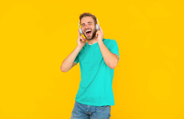 cheerful man in blue shirt wear earphones on yellow background, lifestyle - Fotó, kép