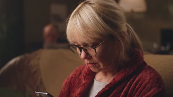 Mujer mayor leyendo noticias impactantes en el teléfono inteligente - Metraje, vídeo