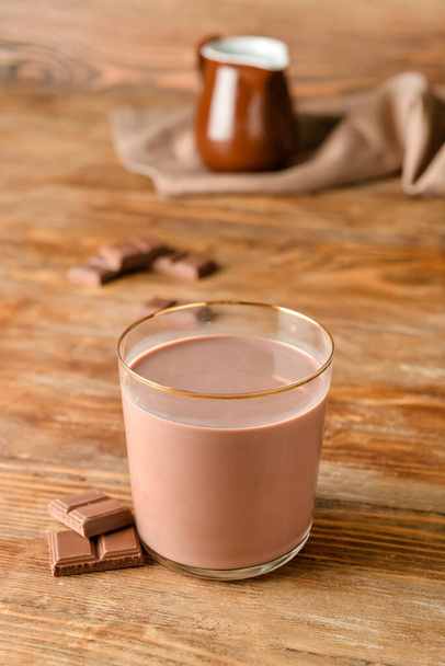 Glass of delicious chocolate milk on wooden background - Фото, зображення