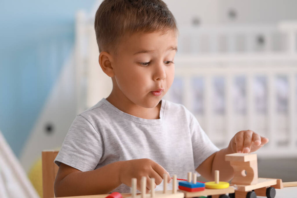 Lindo niño jugando con juguetes de madera en la mesa en la habitación - Foto, imagen