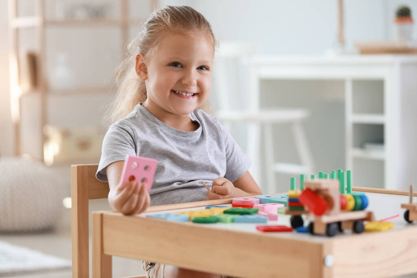Cute little girl playing with building blocks at table in room - Photo, Image