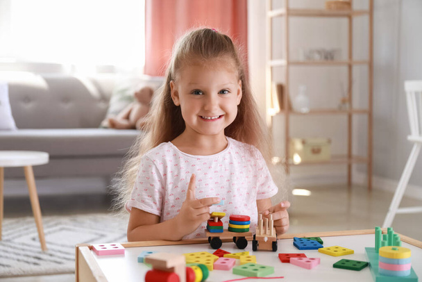 Cute little girl playing with building blocks at table in room - Фото, зображення