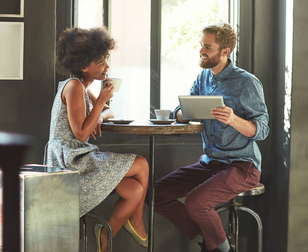 Az első randi. Egy fiatal párról készült felvétel, akik egy digitális táblagépet használnak egy kávézós randin.. - Fotó, kép