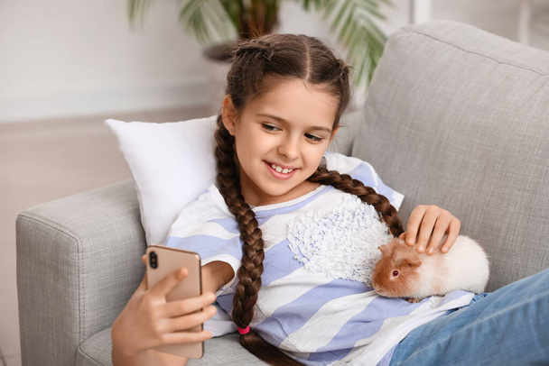 Little girl with cute guinea pig on sofa - Photo, image