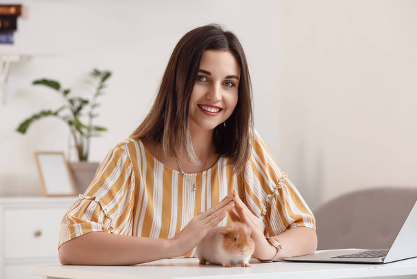 Beautiful young woman with cute guinea pig at home - Photo, Image