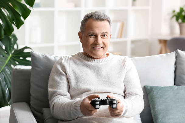 Homme âgé jouant à un jeu vidéo à la maison - Photo, image