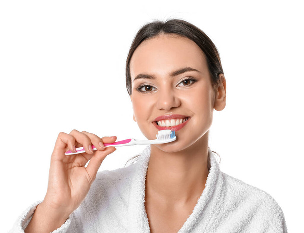 Beyaz arka planda dişlerini fırçalayan güzel genç bir kadın. - Fotoğraf, Görsel