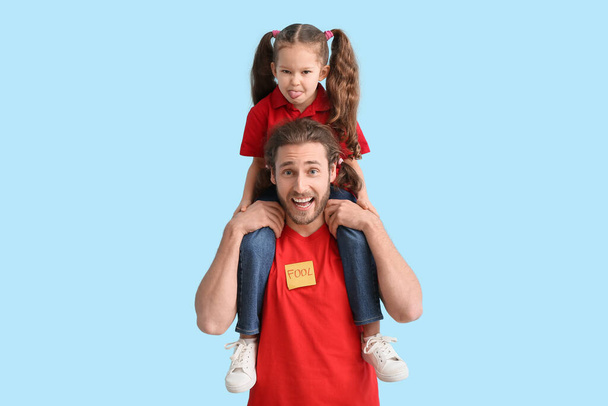 Uomo divertente e sua figlia su sfondo blu. Festa degli sciocchi di aprile - Foto, immagini