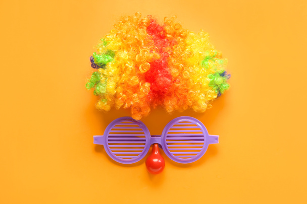 Kompozice s klaunskou parukou a brýlemi na oranžovém pozadí. Dubnová oslava Dne bláznů - Fotografie, Obrázek