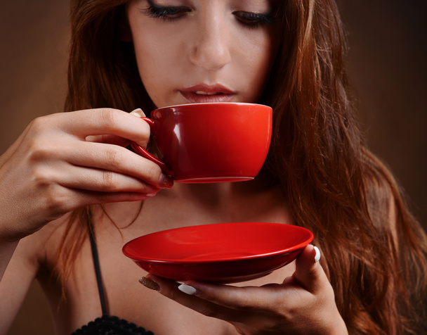 Beautiful young girl with cup of coffee on brown background - Foto, Imagem