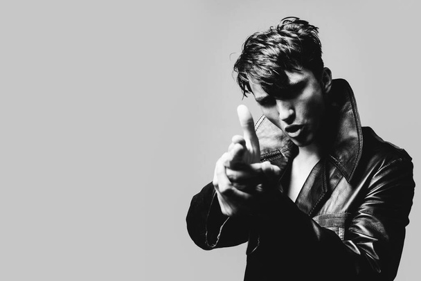 Portrait of handsome man in studio on dark background. Isolated shot of young handsome male make finger gun. - Fotó, kép
