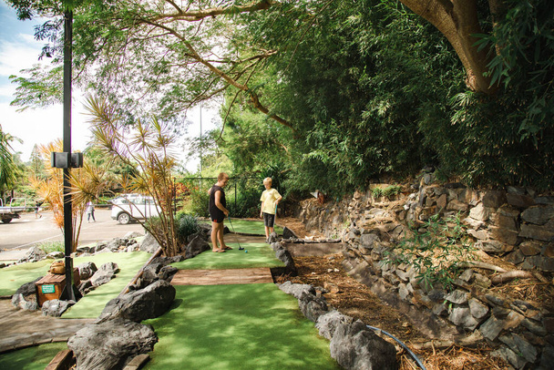 Дети играют в мини-гольф в парке развлечений Big Banana, Кофс-Харбур, Новый Южный Уэльс, Австралия - Фото, изображение