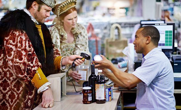 Tenemos un cupón para eso... un rey y una reina comprando comestibles y pagando en el cajero. - Foto, imagen