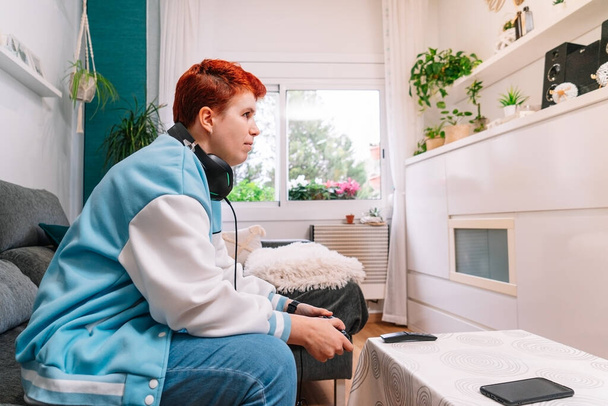 Non-binární osoba hraje videohry v obývacím pokoji doma - Fotografie, Obrázek