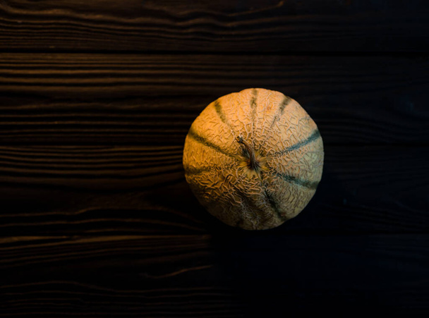 sladký meloun na tmavém pozadí malý lahodný krásný meloun, celý i v kusech a složený k jídlu - Fotografie, Obrázek