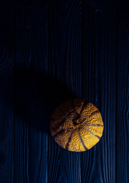 γλυκό πεπόνι σε σκούρο φόντο μικρό νόστιμο όμορφο πεπόνι, ολόκληρο και σε κομμάτια και διπλωμένο για φαγητό - Φωτογραφία, εικόνα