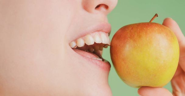 Beautiful young woman eating a apple. Healthy white teeth close up with an apple. - Foto, immagini
