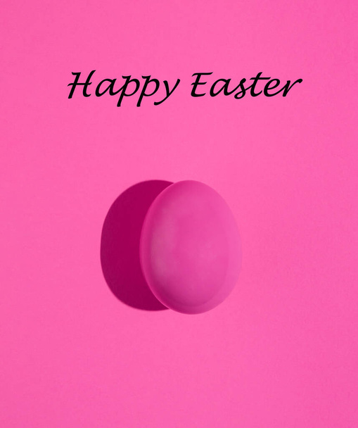 ピンクのイースターエッグがピンクの背景に隔離されています。最小限の休日の概念。単色組成物.ハッピーイースターカード. - 写真・画像
