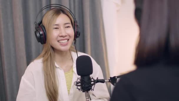Twee jonge Aziatische vrouwelijke blogger gesprekken tijdens het opnemen van podcasts en live streaming op studio werkplek. - Video