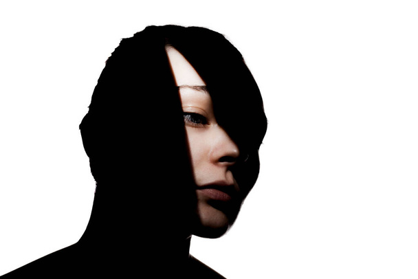 Fashionable studio portrait of a cute girl. Silhouette of a beautiful young woman with hard shadows on her face. against white backgroung. - Photo, image