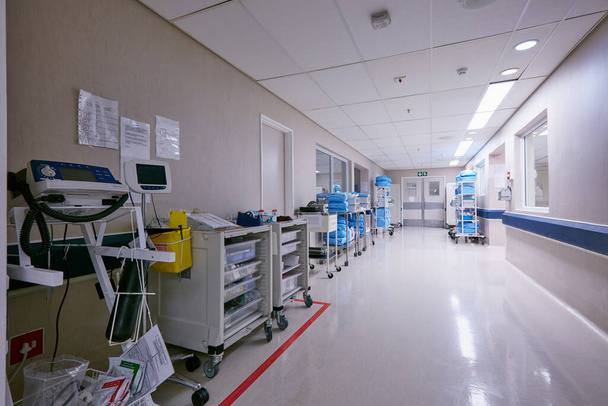 The hallway of healing. Shot of an empty passage way with medical equipment alongside the walls at a hospital. - 写真・画像