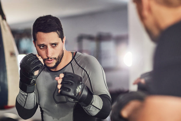 Working on his technique. Cropped shot of two professional fighters sparring in the gym. - 写真・画像