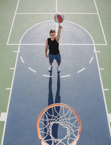 Basketball street player with basketball ball outdoor. Hand spinning basket ball. Balancing basketball on finger. - Foto, afbeelding