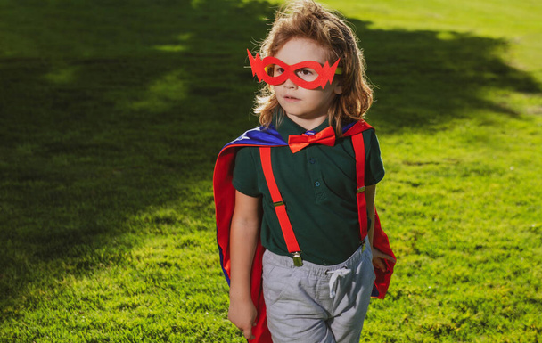 Superhero kid against green background outdoor. Childhood, success and and power concept. - Foto, imagen