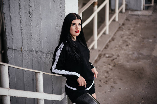 Photo of healthy disabled woman in sportswear with prosthesis leg standing at the stairs and looking aside outdoor - Foto, afbeelding