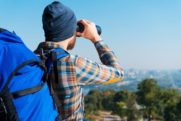 Man carrying backpack and looking through binoculars - 写真・画像