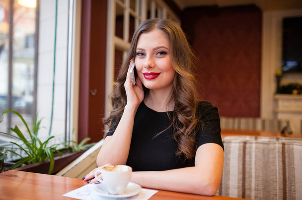 Beautiful girl drinking coffee and talking on the phone - Zdjęcie, obraz