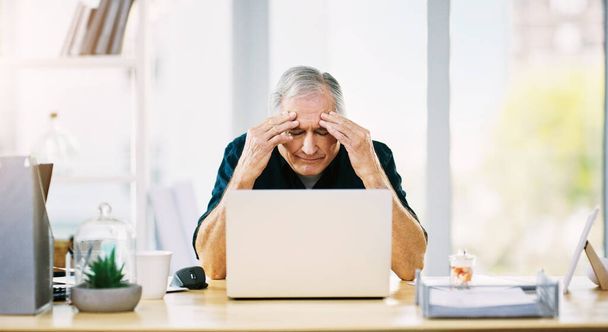 This headache isnt helping matters either. Shot of a mature businessman suffering from a headache in his office. - Foto, Imagen