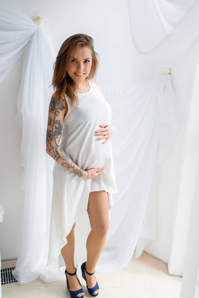 Happy pregnant girl in white dress. - Фото, изображение