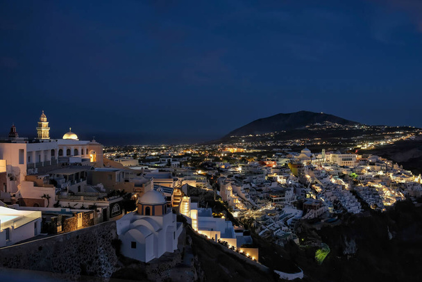 Панорамный вид на освещенную иллюминацией деревню Фира Санторини Греция в ночное время - Фото, изображение