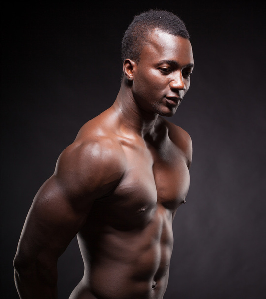Beautiful and muscular black man in dark background - Foto, afbeelding