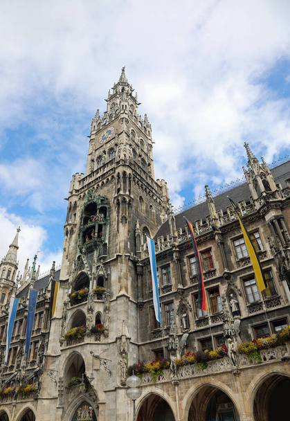 City hall with tall bell tower on Marienplatz in Munich with flags of the city and germany - Photo, Image
