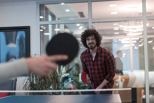 Two young start up business man playing ping pong tennis at modern creative office space people group have meeting and brainstorming in background - Photo, image