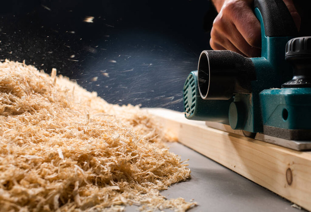 trabajador cepillando una mesa de madera con un plano eléctrico
. - Foto, imagen