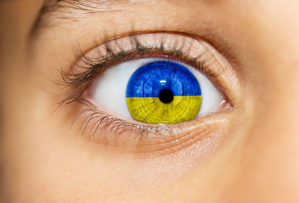 Reflection of the flag of Ukraine in the frightened eye of a little girl. - Foto, afbeelding