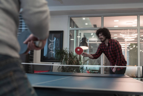 Two young start up business man playing ping pong tennis at modern creative office space people group have meeting and brainstorming in background - Photo, image