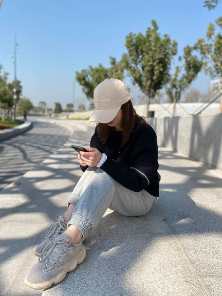 young woman using mobile phone while sitting on bench - Φωτογραφία, εικόνα