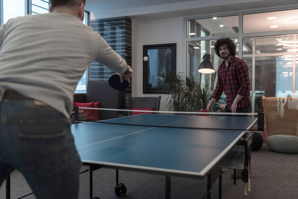 Two young start up business man playing ping pong tennis at modern creative office space people group have meeting and brainstorming in background - Fotó, kép
