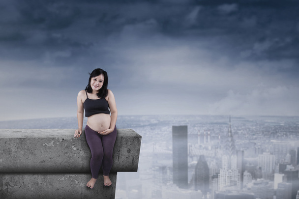 Pregnant mother sitting on rooftop - Foto, imagen