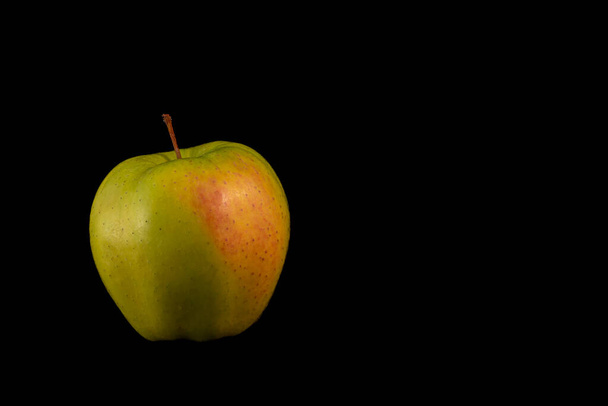 una jugosa manzana amarilla sobre un fondo negro - Foto, Imagen